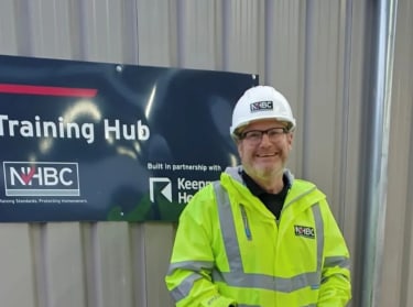 a man wearing hi-vis jacket and helmet smiling at the camera