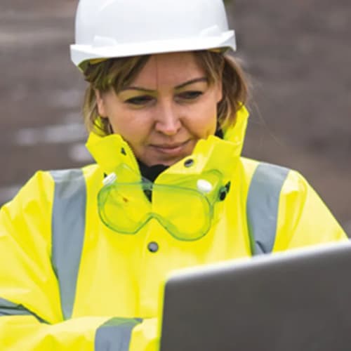 Woman looking at ipad with safety jacket and hard hat