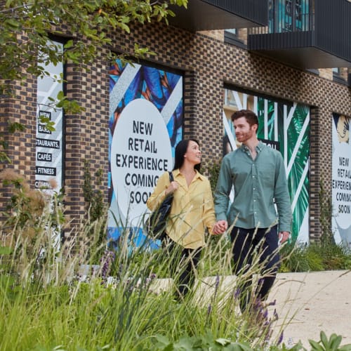 Couple holding hands and walking past new build homes
