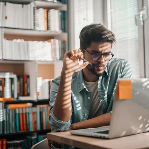 Man looking at a laptop with post it note