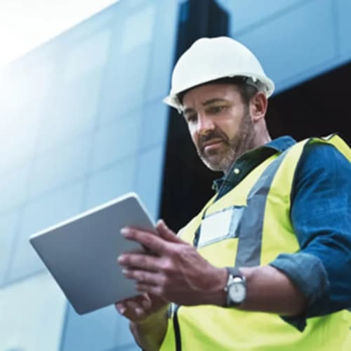 Man with safety jacket and hard hat using pad
