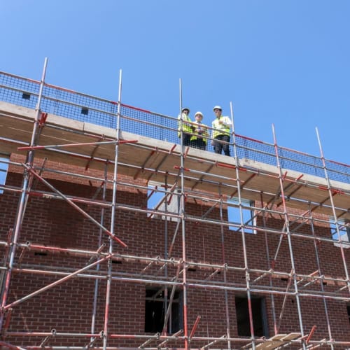 NHBC team standing on roof of building in development with scaffolding