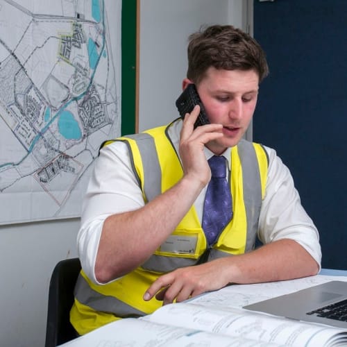 Man speaking on mobile phone while in office wearing his vis vest