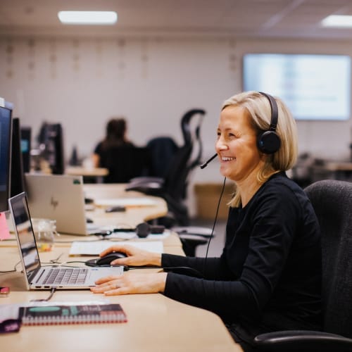 a woman wearing a headset at her computer smiling