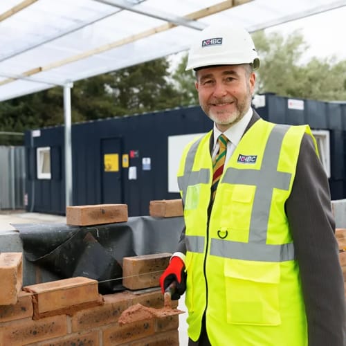person with high-vis jacket and hardhat smiling at camera