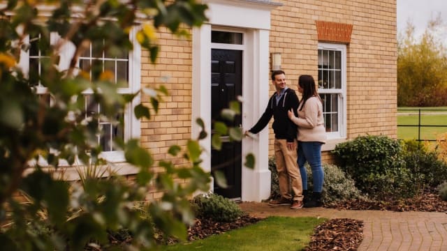 Couple smiling entering the front door of a new build home