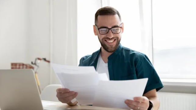 a man looks at paper documents while smiling