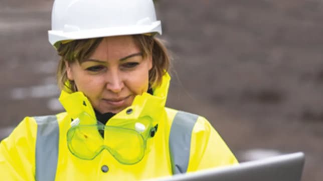 Woman looking at ipad with safety jacket and hard hat