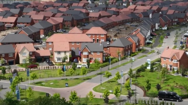 a drone shot of a new build development with red brick houses and green areas