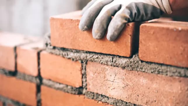 Close up view of gloved hands laying bricks