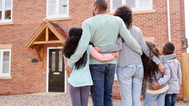 Family of five embracing looking at new build home
