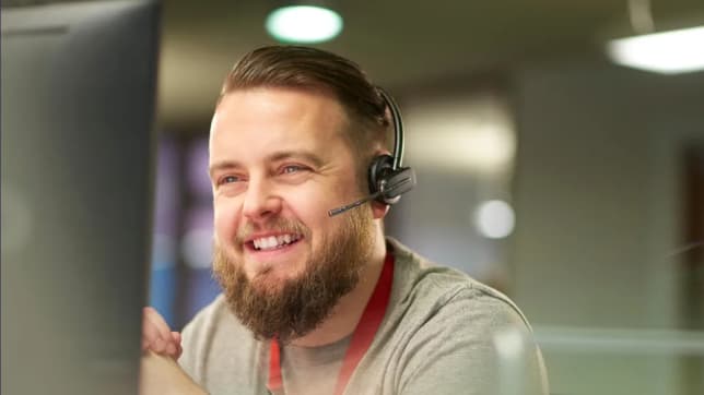 Smiling man with headset on looking at laptop