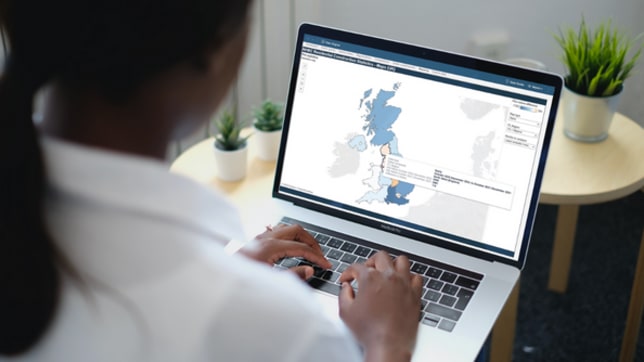 Office worker looking at highlighted map of united kingdom on their laptop