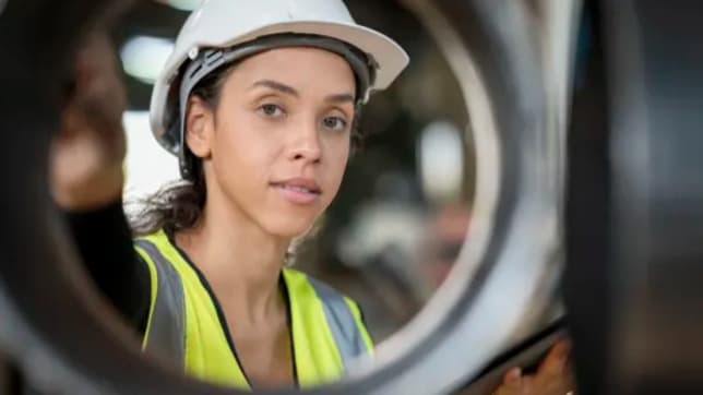 Women in yellow high vis looking through a round steel structure