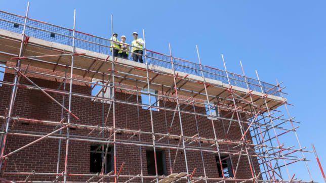 NHBC team standing on roof of building in development with scaffolding