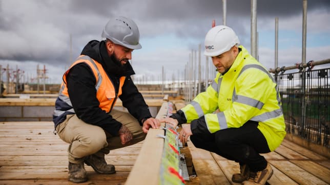 Two men in hi-vis jackets inspecting a building