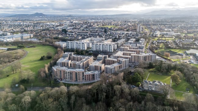 a drone shot of high-rise buildings and green fields