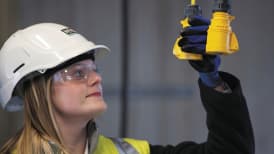 a woman on site, wearing a high vis vest and a hard hat, inspecting a pulley