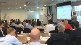 a photo of people sat at tables during the construction quality forums event