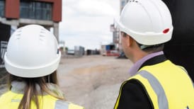 a man and a woman in site safety clothing and hard hat looking at a site