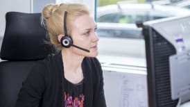 a woman sat at her desk talking into a headset