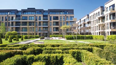 white and beige block of flats with a large green area in the centre