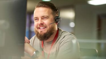 a man wearing a headset sat at a desk smiling