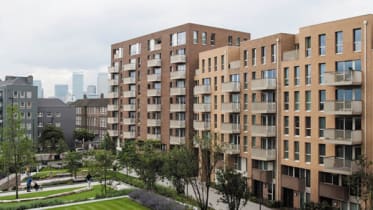 two modern, beige blocks of flats with glass balconies