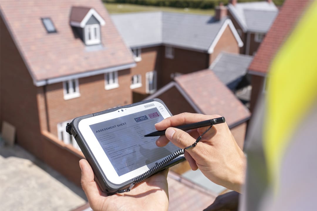 someone wearing site safety clothing reading a tablet with nhbc's best practices to roofs