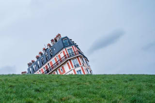 The upper part of an old building appears to be collapsing to one side and disappearing underground.