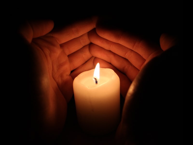 Hands covering a candle