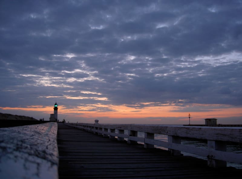 A photo of a pier and lighthouse in sunset