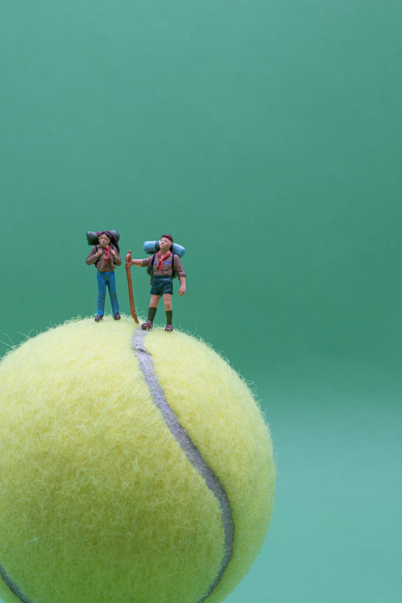 Photo of miniature figures of boy scouts hiking on a tennis ball