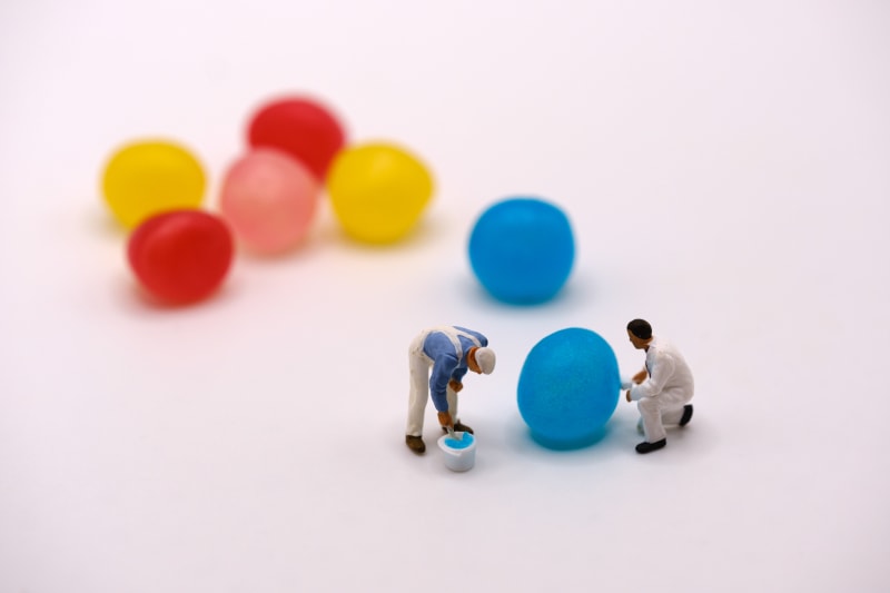 Photo of dragibus candies of different colors, with tiny figurines pretending to paint them