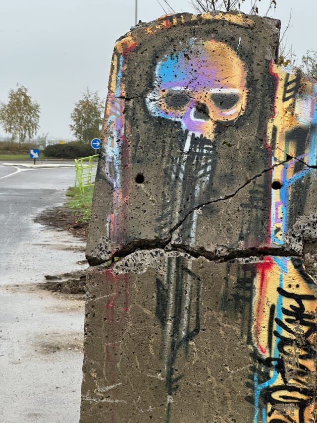 Un dessin de tête de mort sur un poteau en béton cassé