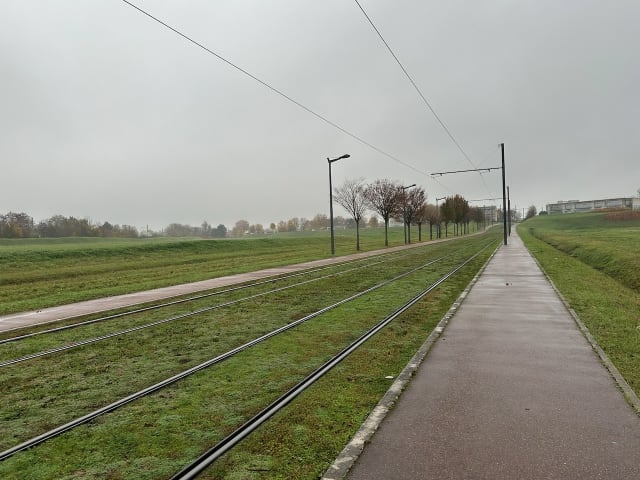 Une piste cyclable dans la nature, qui suit les rails du tramway