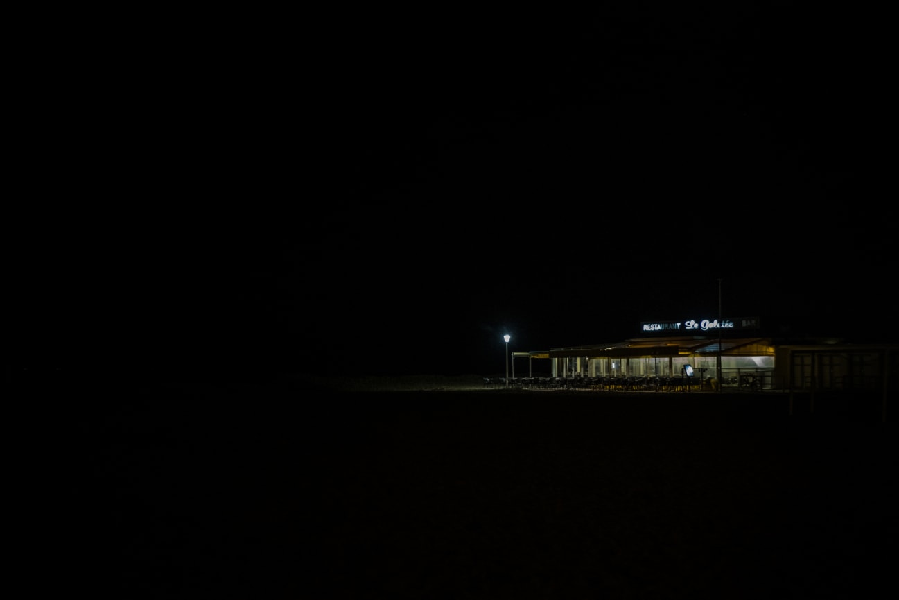 The terrace of a lighted restaurant, emerging from a very dark night