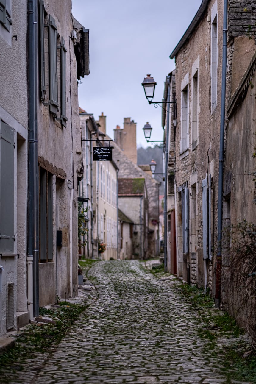 Photo of a small cobbled street, with a sign on one wall reading "Le Gratin Mondain".