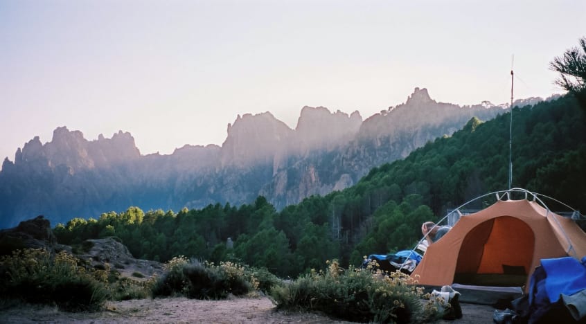 Photo of sunbeams on the mountain, with a tent in the foreground