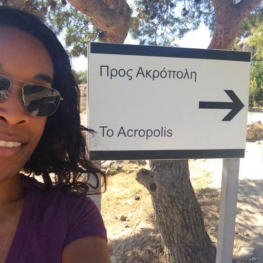 Me standing next to a sign that says TO ACROPOLIS