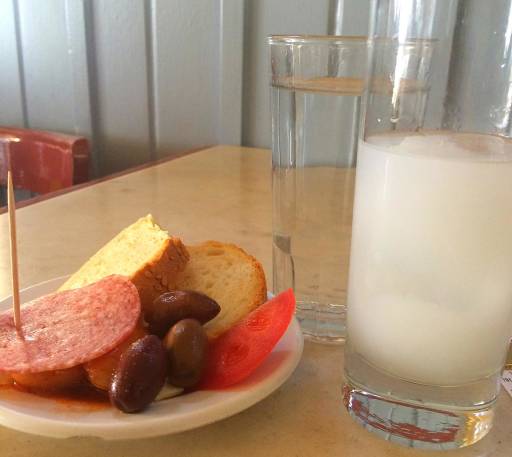 A plate of nibbles and a glass with a cloudy white icy drink