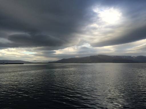 Vast sea with ominous clouds and mountains in the background