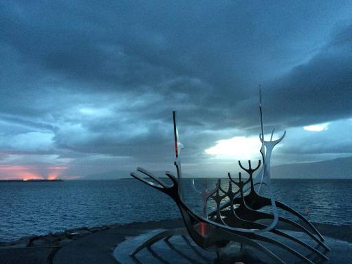 A metal boat skeleton statue next to the sea