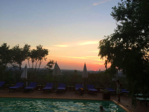 Sunset in the far distance with a luxe pool and deck in the foreground