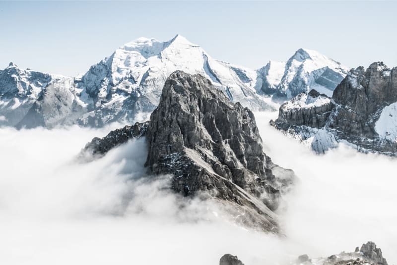 High mountains piercing through the clouds, some covered in snow