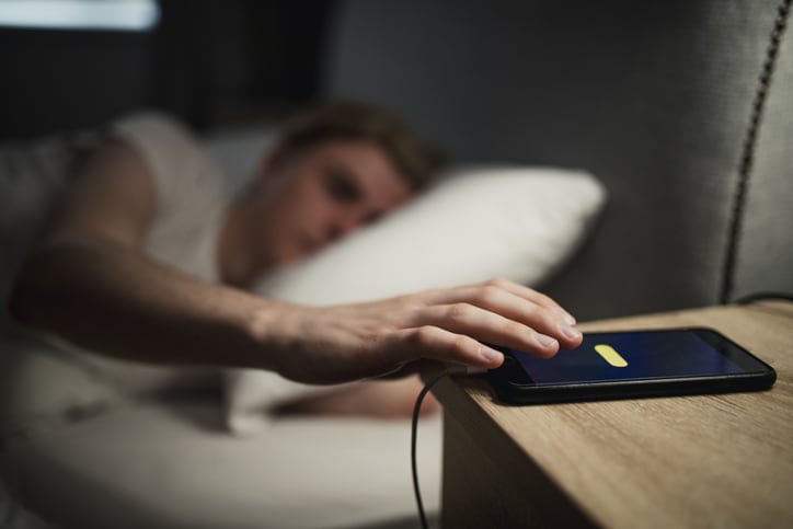 Man Reaching to turn off his phone alarm