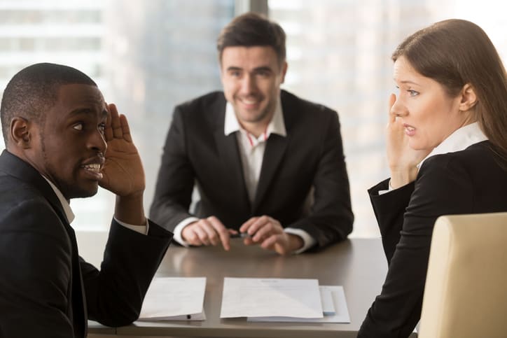 Multiracial confused employers covertly discuss job applicant, hide face with hands, look puzzled bewildered, secretly whisper during failed interview, bad negative first impression, make decision