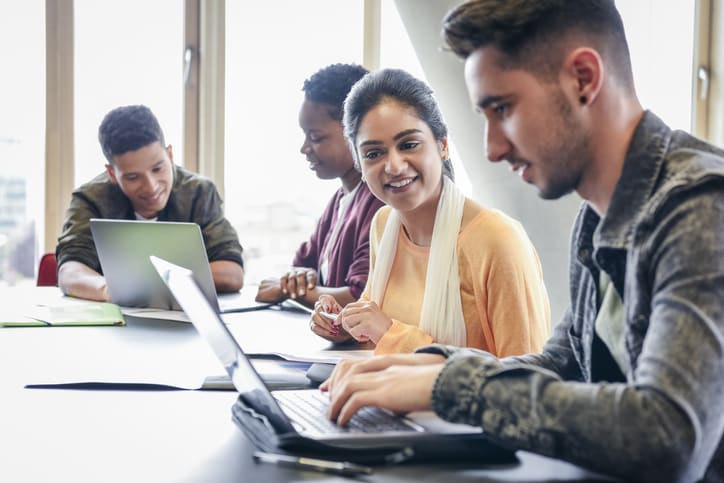 College students working on computer in classroom, young adults in further education, man concentrating as he types on keyboard