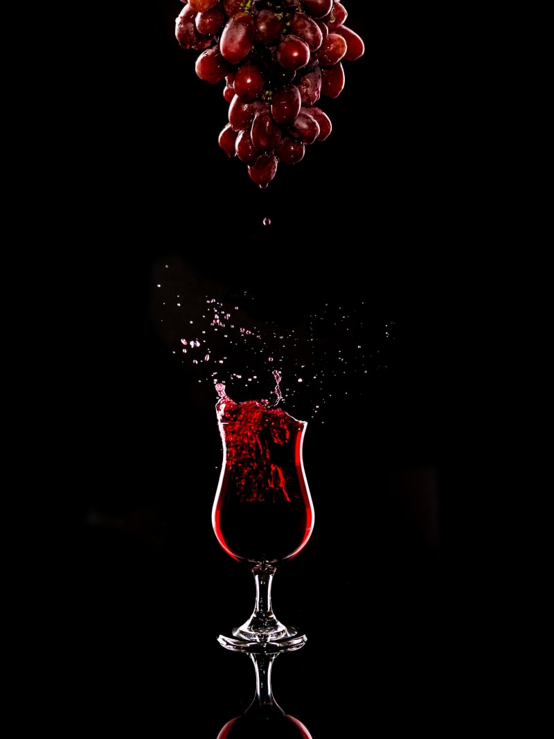 Red Wine Splash Grapes Glass Black Background Dramatic