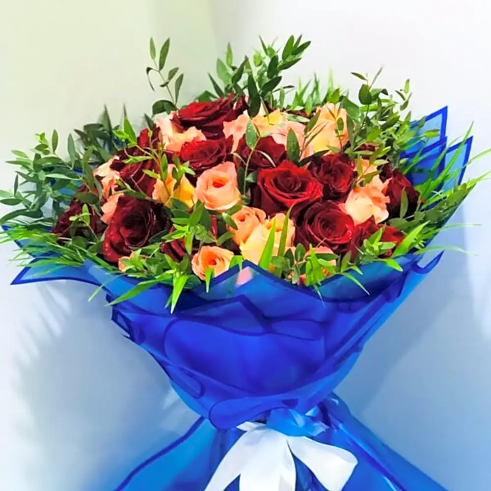 Bouquet of peach flowers and red roses with areca leaves and wrapped in blue paper N